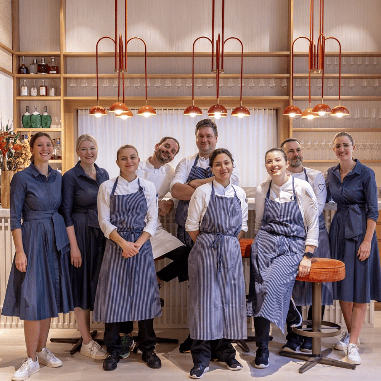 Küchen- und Serviceteam des KOMU in blauen Schürzen vor der Bar