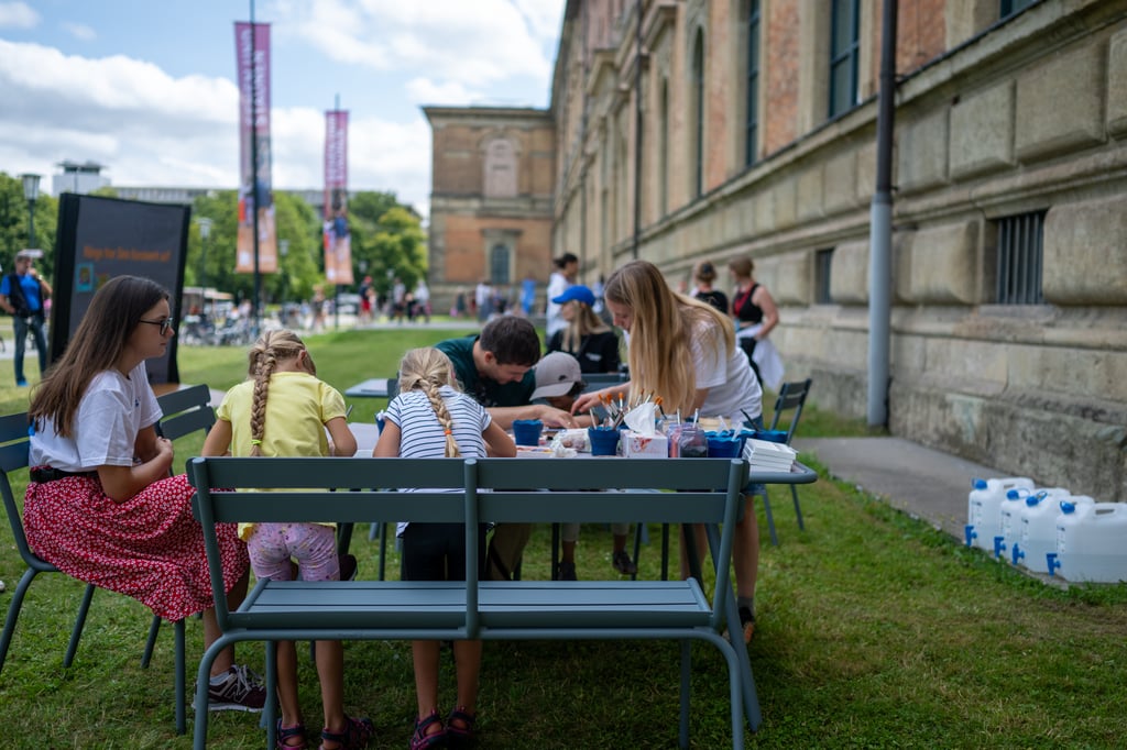 Kinder und Jugendliche malen gemeinsam im Freien beim Kunstareal-Fest München, kostenloses Kreativangebot auf der Wiese vor der Alten Pinakothek