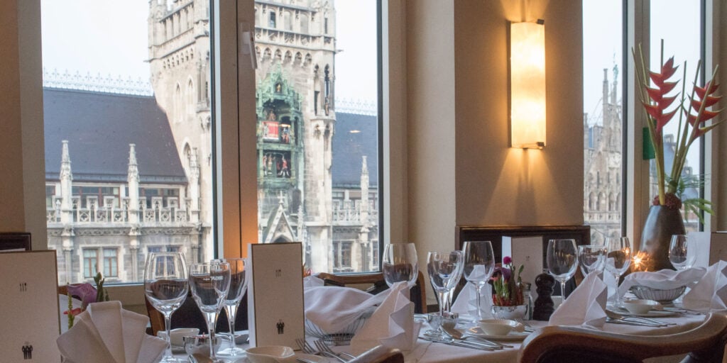 Blick aus dem Café Glockenspiel über gedeckte Tische auf das Neue Rathaus am Marienplatz