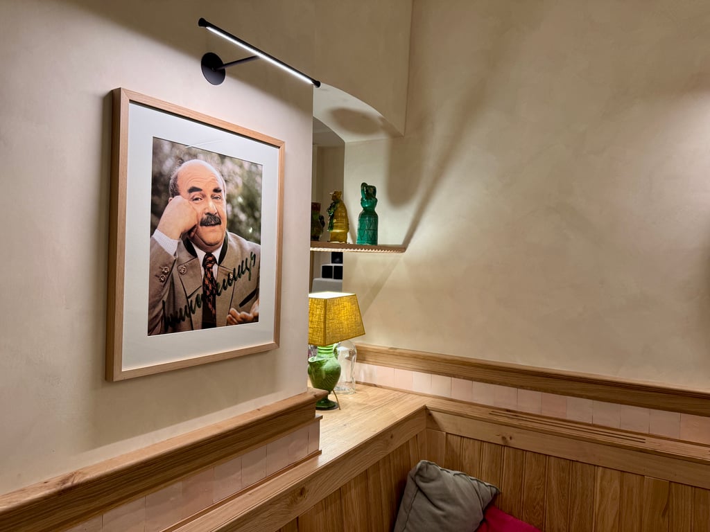 Framed photograph of a man in a suit resting his chin on his hand on a beige wall.