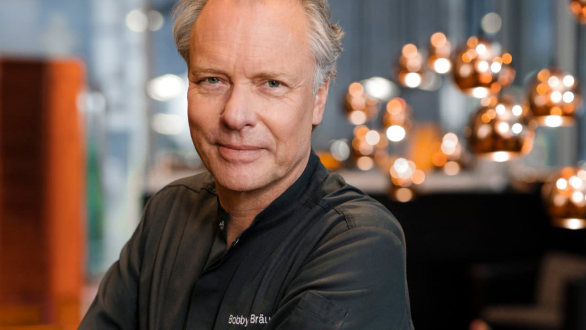 Bobby Bräuer im Porträt vor kupferfarbenen Pendelleuchten