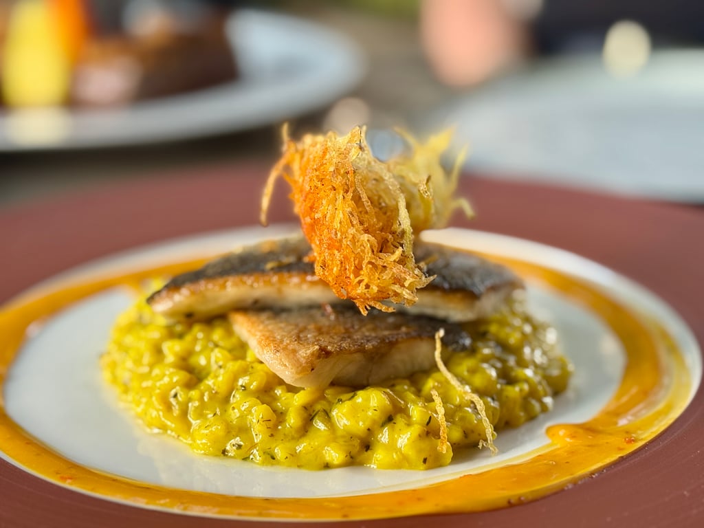 Close-up of a creamy yellow risotto topped with a crispy fried garnish on a decorative plate.
