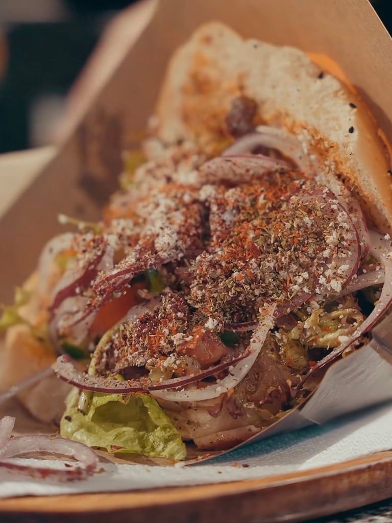 Close-up of a loaded beef taco with onions, lettuce, and herbs in a warm tortilla on a plate.