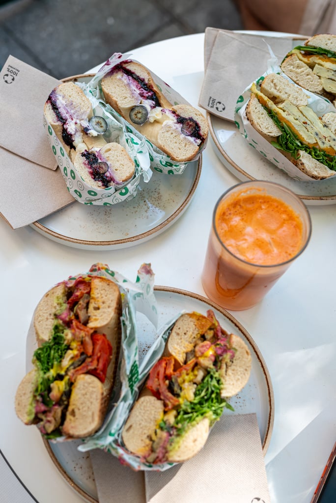 Close-up of multiple baguette-style sandwiches with colorful fillings (greens, tomatoes, cheese) arranged on ceramic plates with napkins nearby.