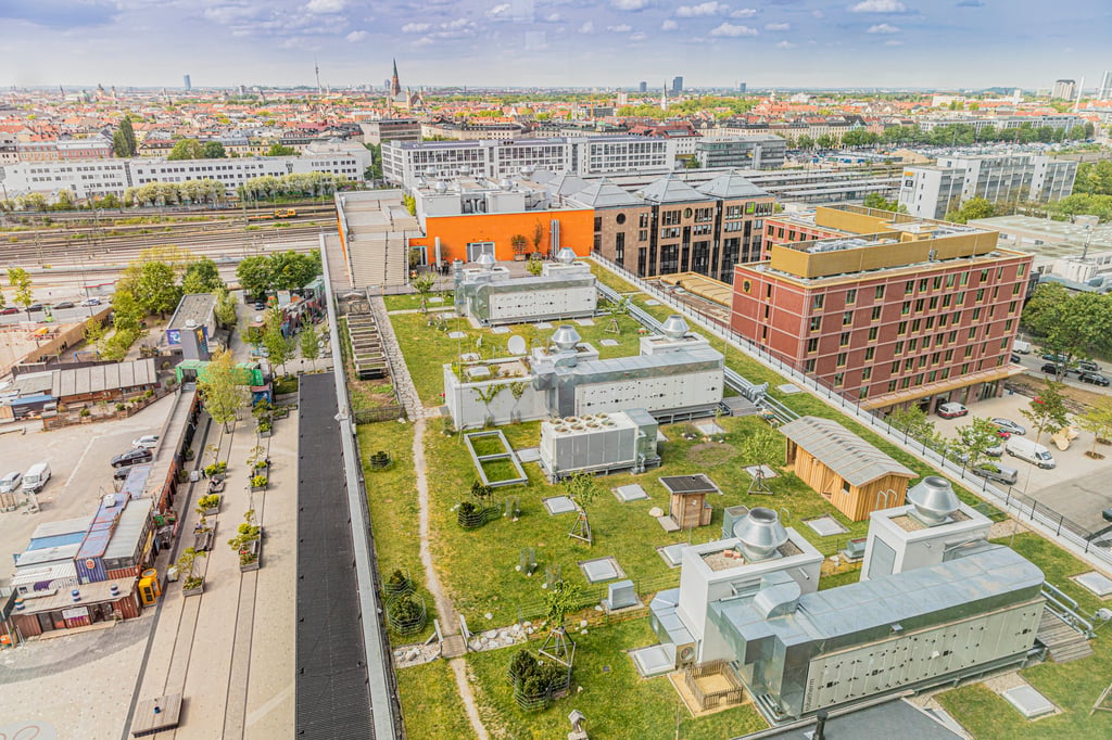 Aerial view of a cityscape with rails in the foreground, orange and brick buildings, and green rooftop spaces.