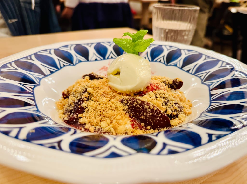 Dessert plate with crumb topping, a scoop of vanilla ice cream, and a mint garnish on a blue patterned plate