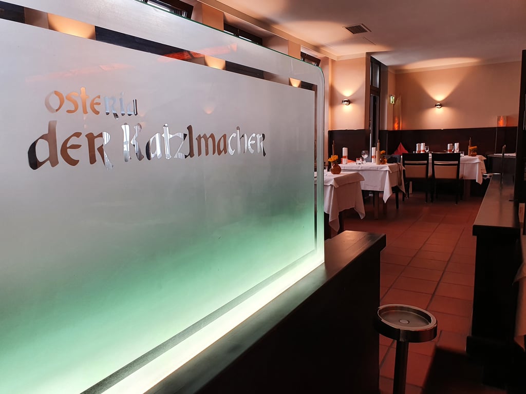Frosted glass divider with etched letters in a warm dining room, white-tablecloth tables, yellow flowers, and soft ambient lighting.