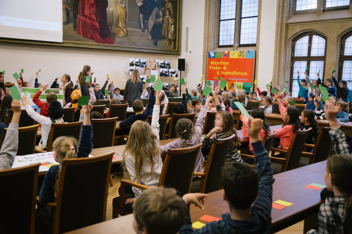 Kinder stimmen mithilfe von grünen, gelben und roten Karten ab im Münchner Rathaus beim Kinder- und Jugendforum