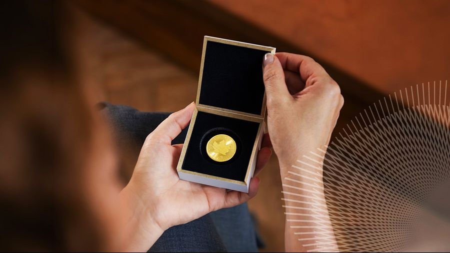 Person holding an open small box with a gold medal resting in a black velvet insert, ready for presentation.