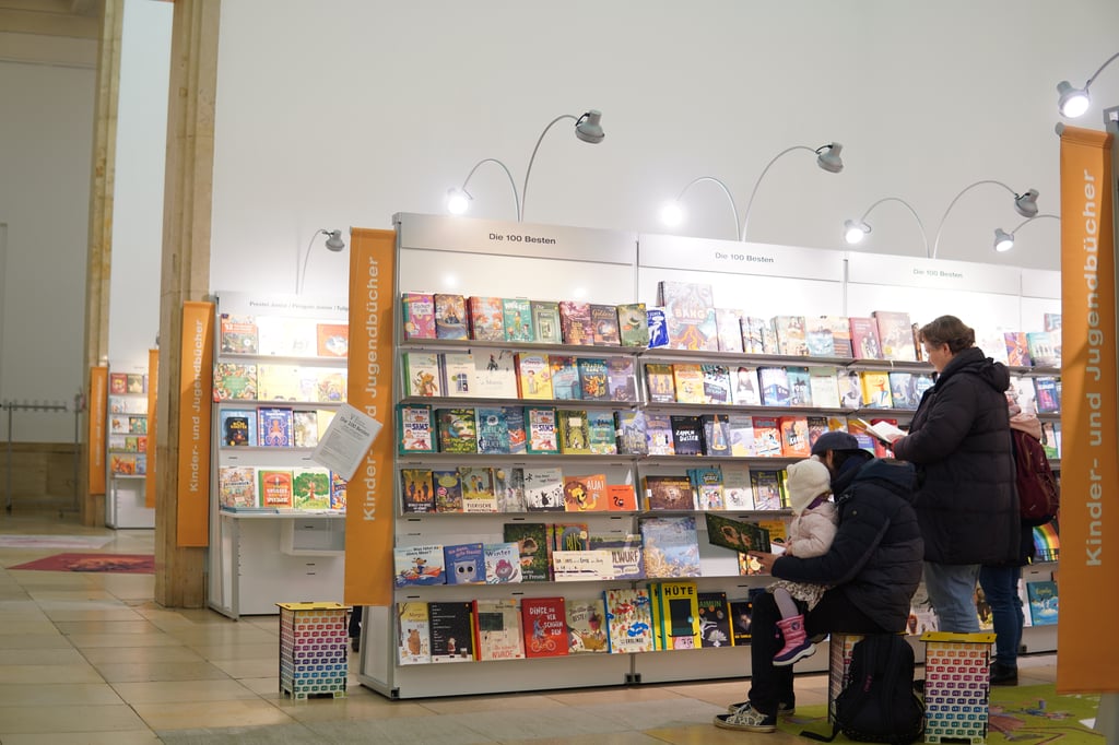 Familie liest vor Regalen bei der Münchner Bücherschau