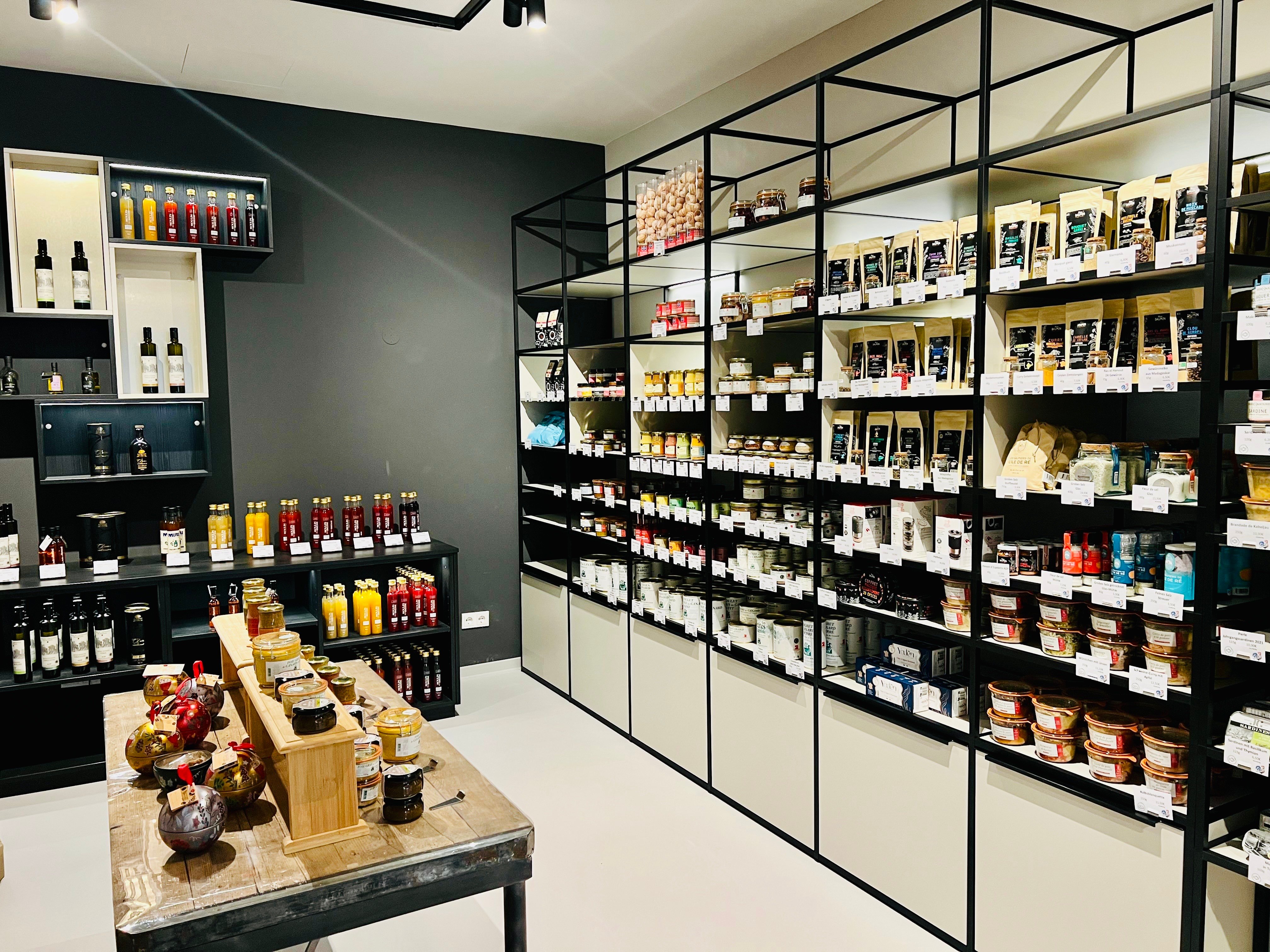 Feinkostladen mit schwarzen Metallregalen voller Delikatessen und Weinflaschen bei Chez Pierre