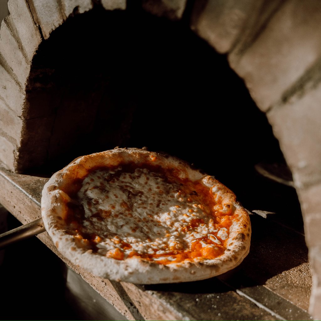 Pizza with bubbling cheese and tomato sauce baking in a brick oven.
