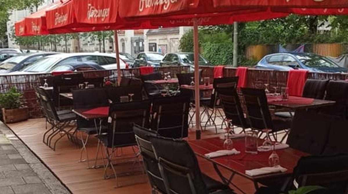 Terrasse der Maison Massard mit roten Schirmen an der Bazeillesstraße