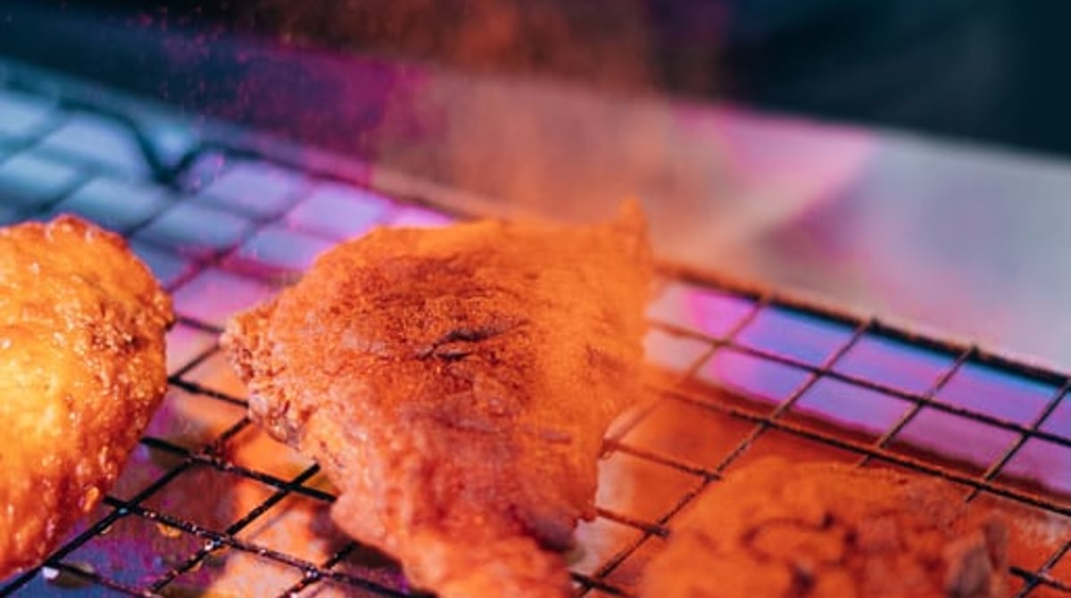 Fried Chicken auf dem Gitterrost wird gewürzt