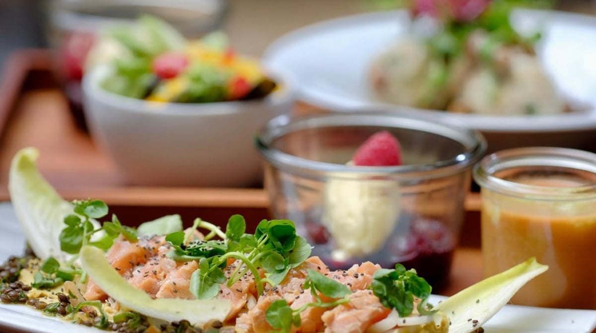 Vorspeise mit Chicorée und Salat, daneben kleine Gläser und Schalen auf einem Holztablett