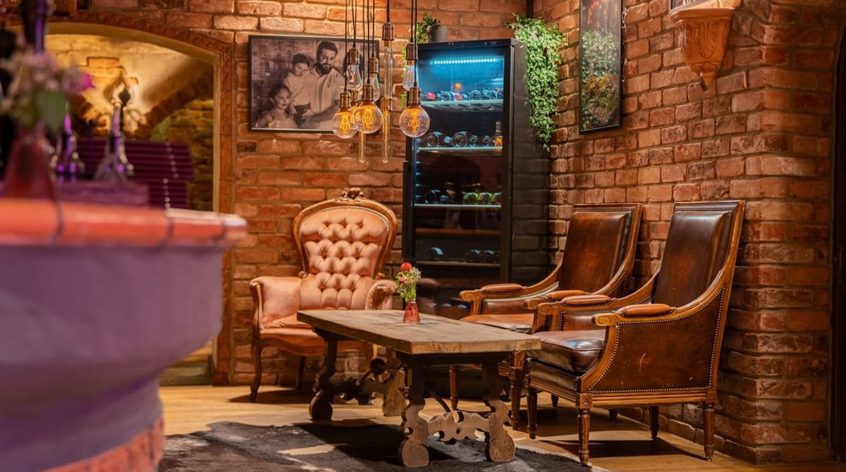 Lounge-Ecke mit Ledersesseln, Ziegelwand und Weinkühlschrank in der Pablo Emilio BurgerBar