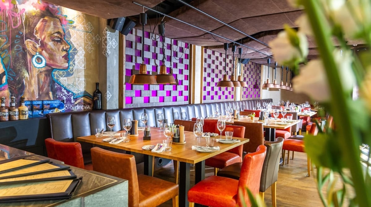 Gastraum des El Gaucho mit buntem Wandbild und Sitzbank