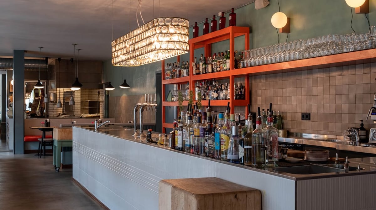 Bar im Theresa mit orangefarbenem Regal voller Flaschen und weißer Theke