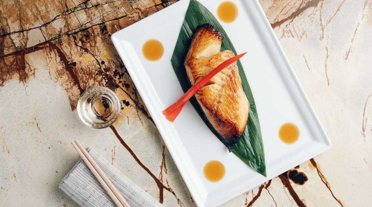 Gebratener Black Cod auf Bambusblatt, angerichtet auf einem weißen Teller