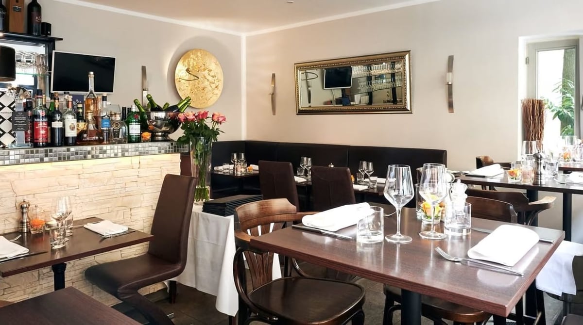 Gastraum des Cupido im Lehel mit gedeckten Tischen, Bar und goldenem Wandschmuck