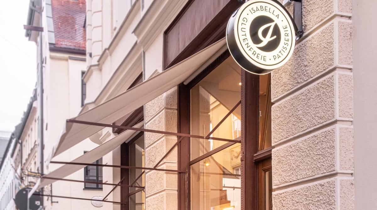 Außenansicht der Isabella Glutenfreien Pâtisserie in der Hackenstraße mit Hängeschild, Markise und Schaufenster