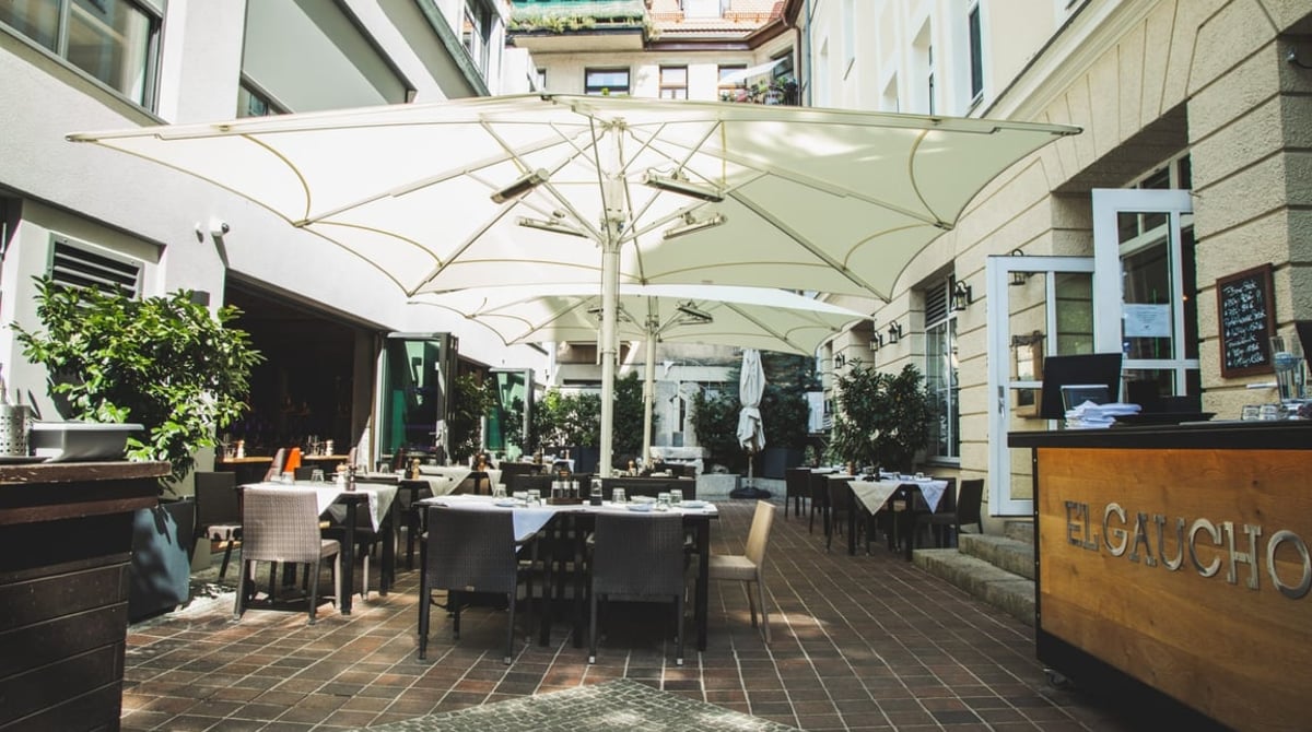 Außenbereich mit großen weißen Sonnenschirmen vor dem El Gaucho