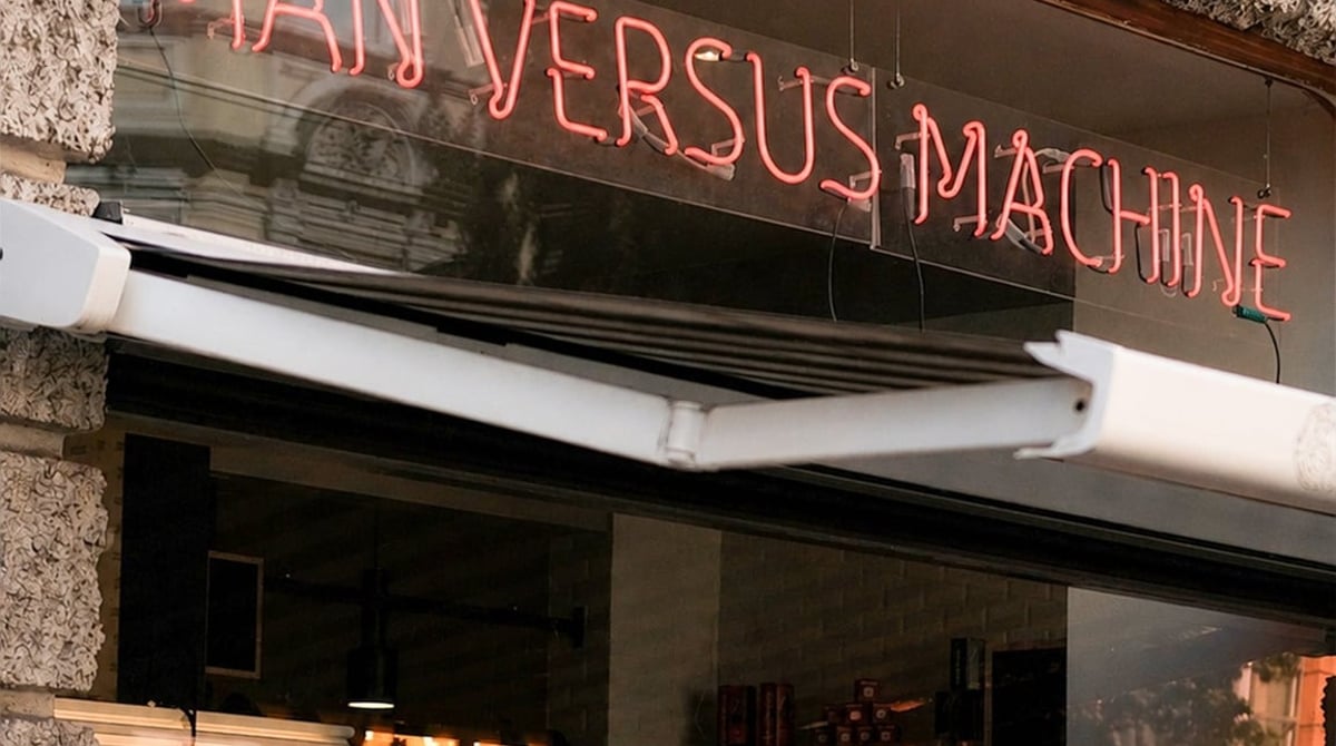 Neonschriftzug Man Versus Machine über dem Schaufenster des Cafés in der Müllerstraße im Glockenbachviertel