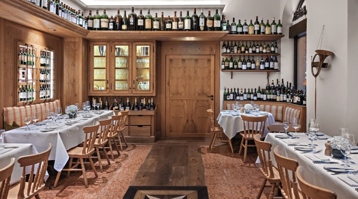 Langer gedeckter Tisch vor beleuchteten Weinschränken aus Holz