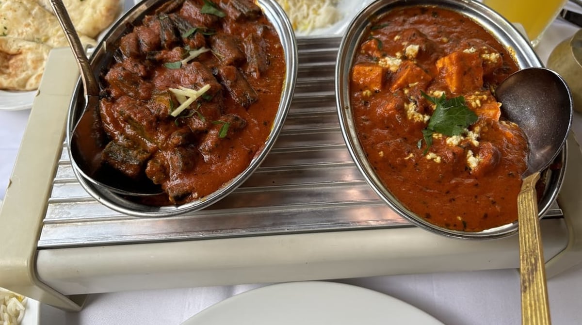 Lammcurry und Paneer-Curry in Metallschalen, dazu Nan und Reis