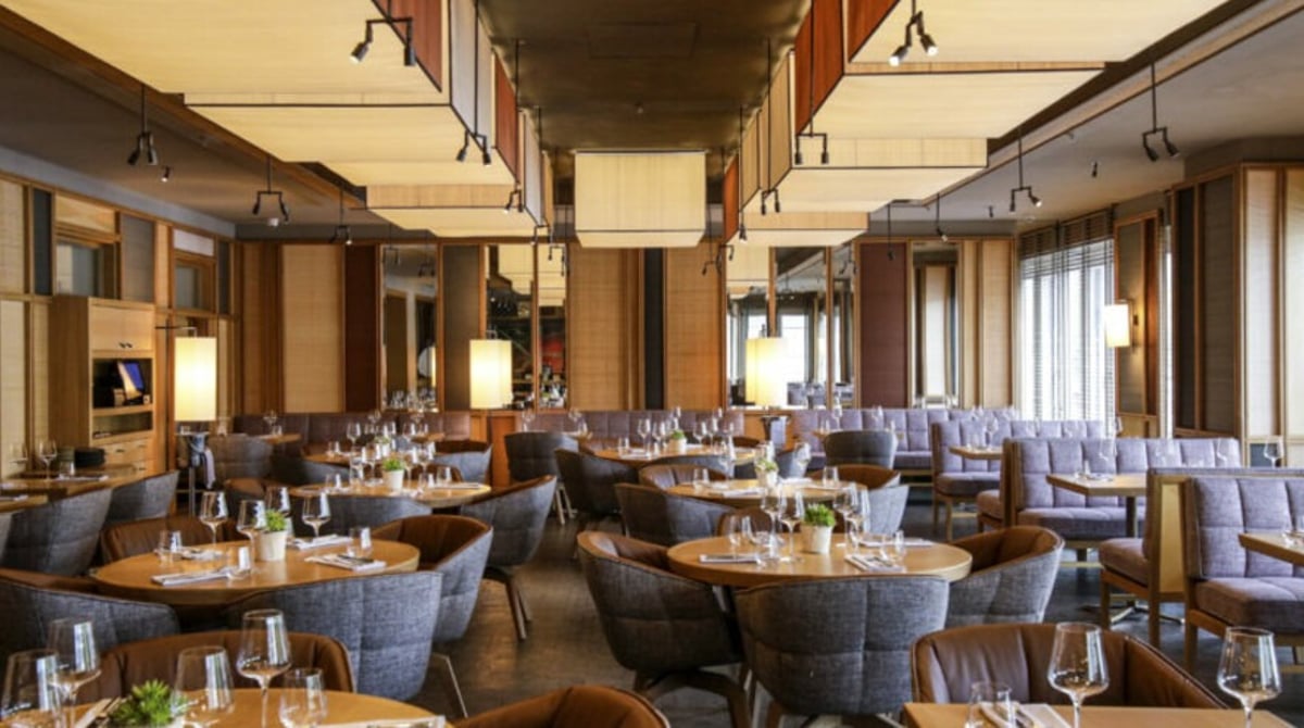 Weiter Gastraum des LOUIS Grillroom mit Fensterfront und gedeckten Tischen