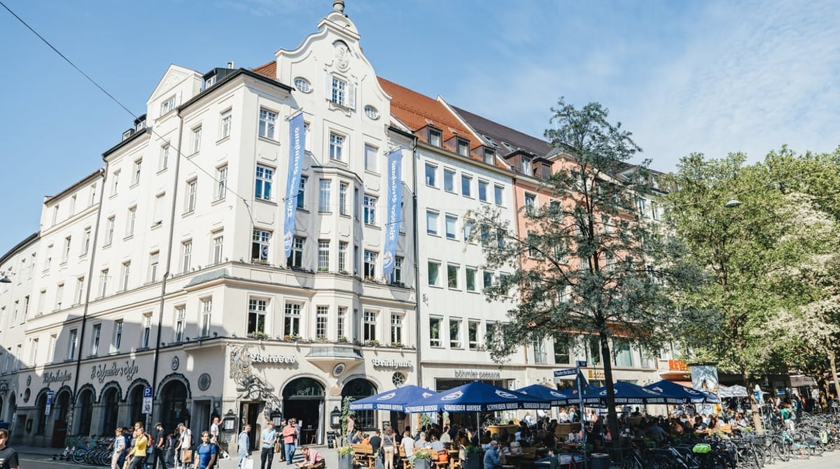 Außenansicht des Weissen Bräuhauses im Tal in München mit Terrasse und blauen Sonnenschirmen