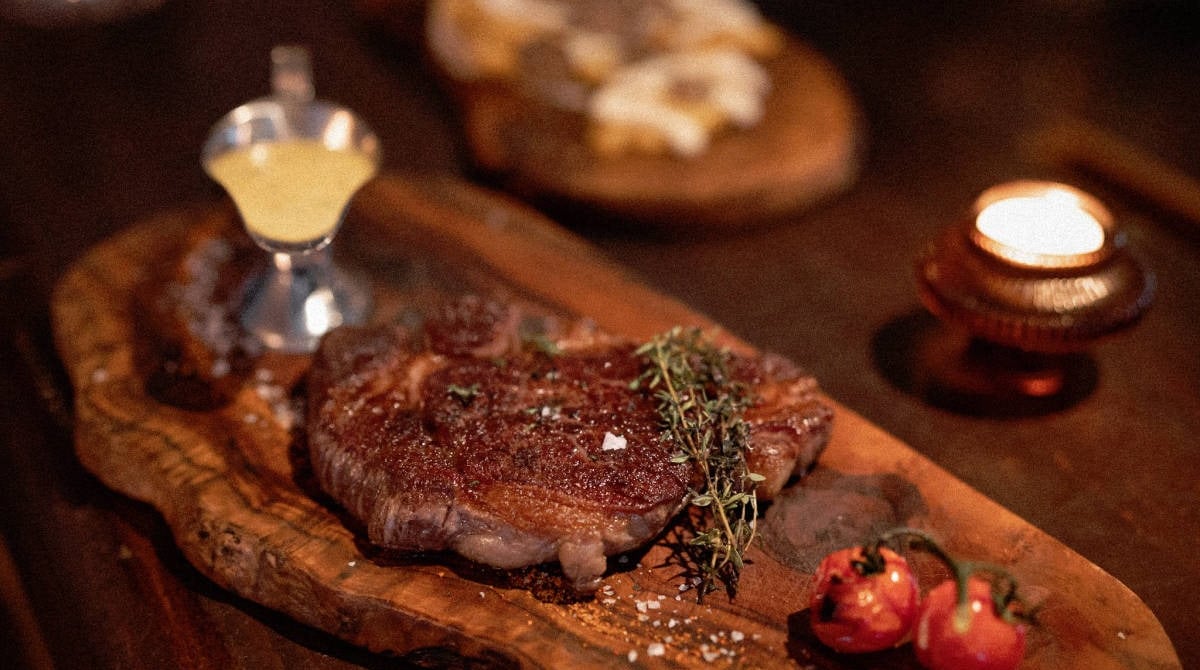 Gegrilltes Steak mit Thymian und Kirschtomaten auf einem Holzbrett