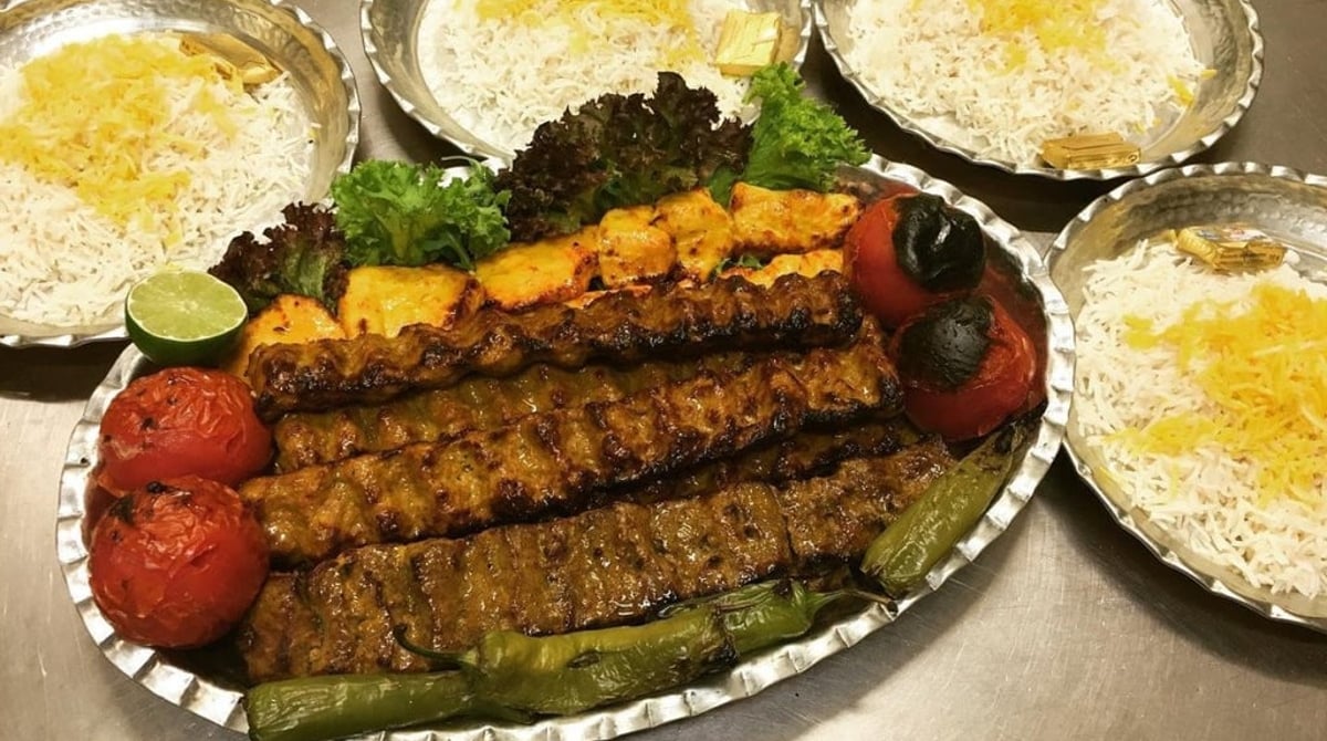 Gemischte Kebab-Platte mit Safranreis, gegrillten Tomaten und Kräutern im Dehbaschi