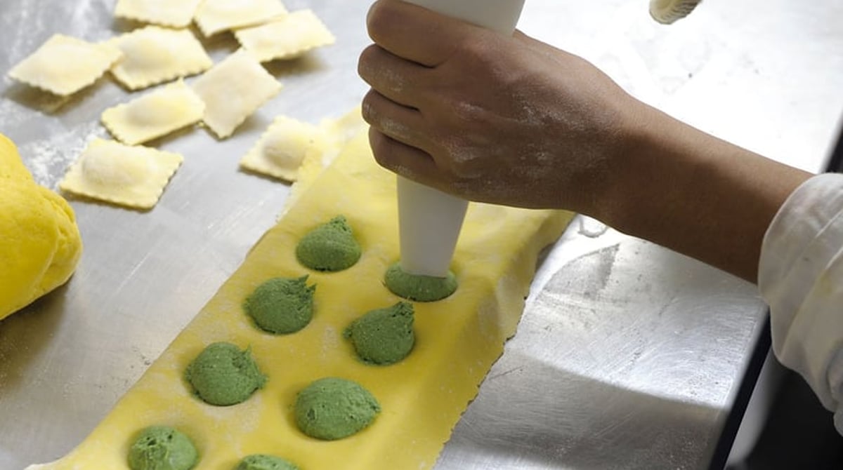 Frische Ravioli werden mit grüner Füllung gespritzt