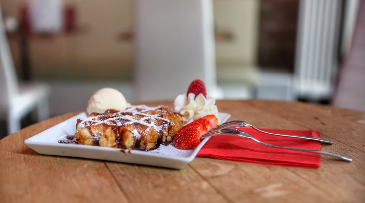Waffel mit Vanilleeis, Erdbeeren und Sauce auf einem Teller