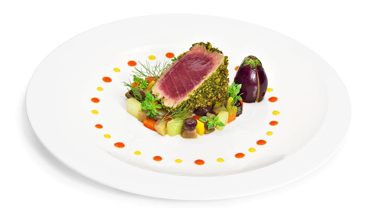 Gebratener Thunfisch mit Kräuterkruste auf einem weißen Teller
