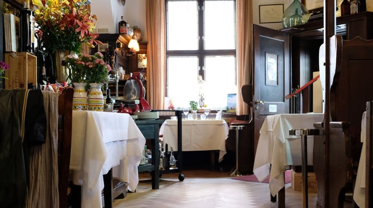 Gastraum der Osteria Italiana mit weiß eingedeckten Tischen und Fischgrätparkett