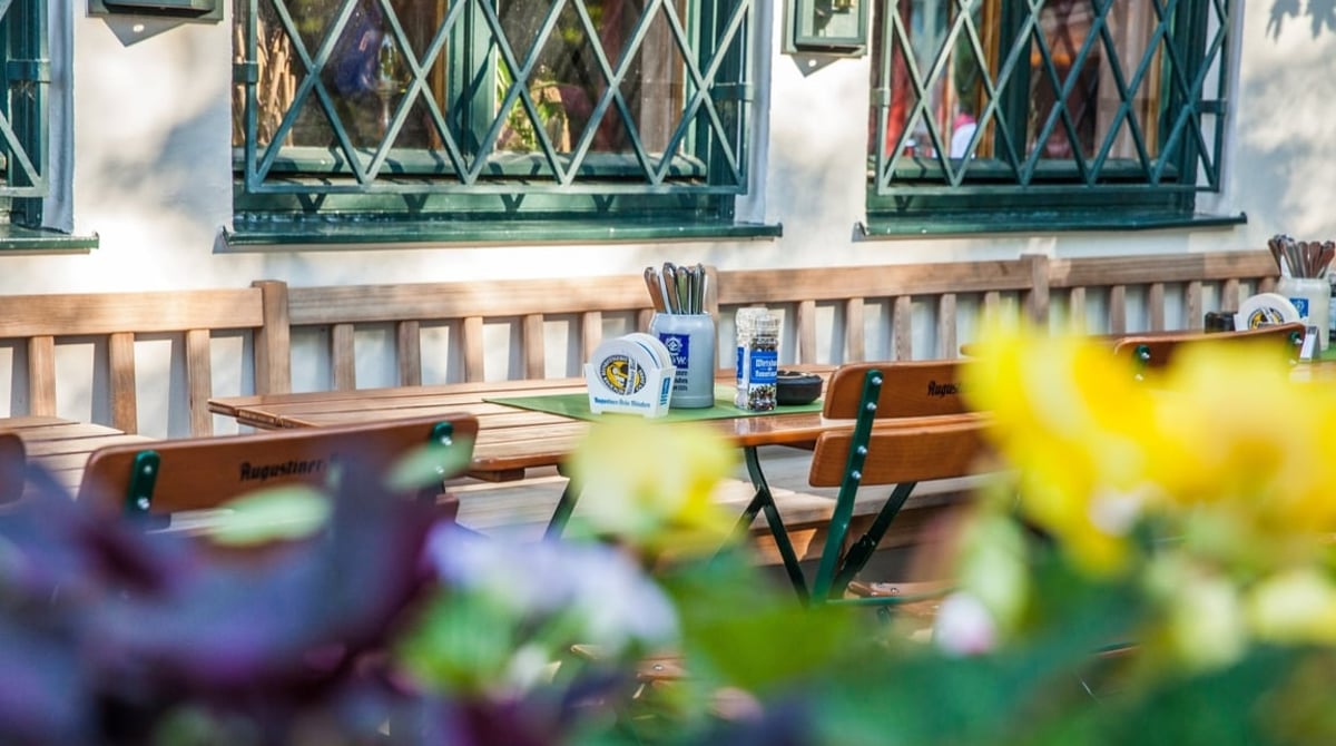 Biergartentische mit Blumen vor der Fassade des Wirtshauses