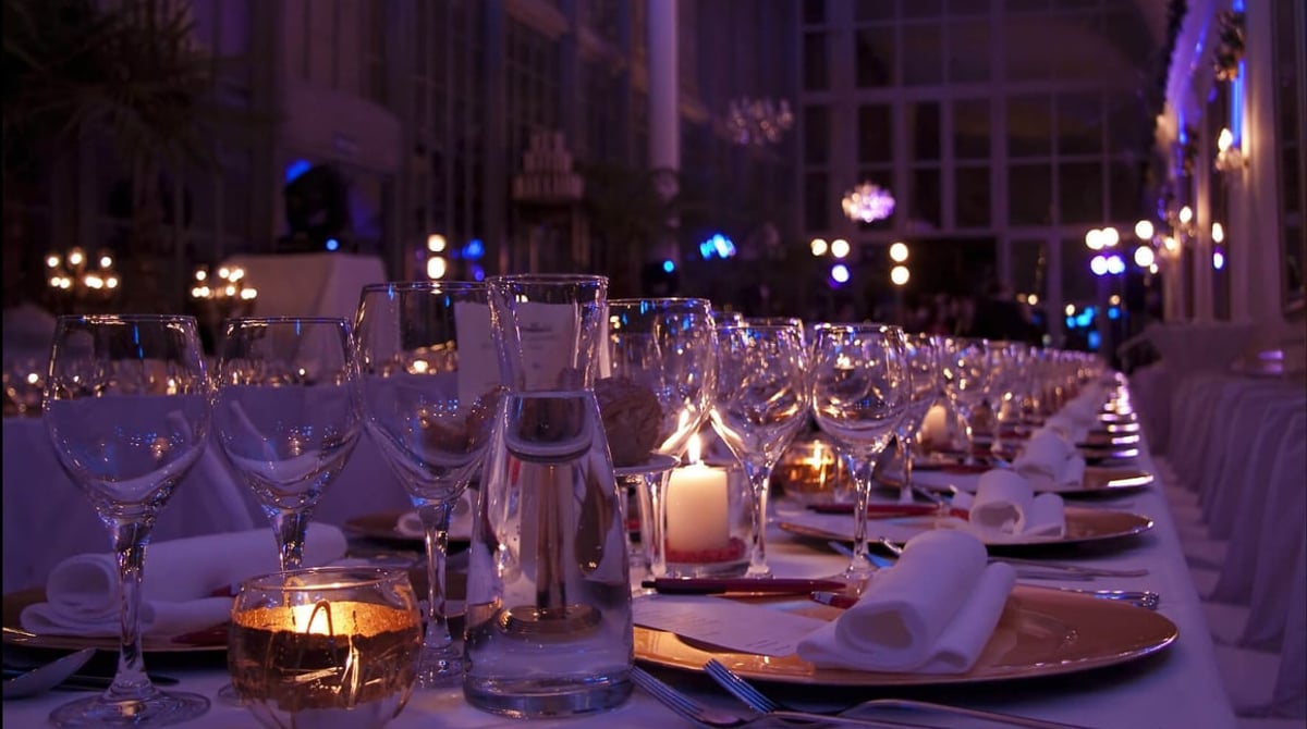 Festlich gedeckte Tafel am Abend vor den Glasfenstern des Palmenhauses