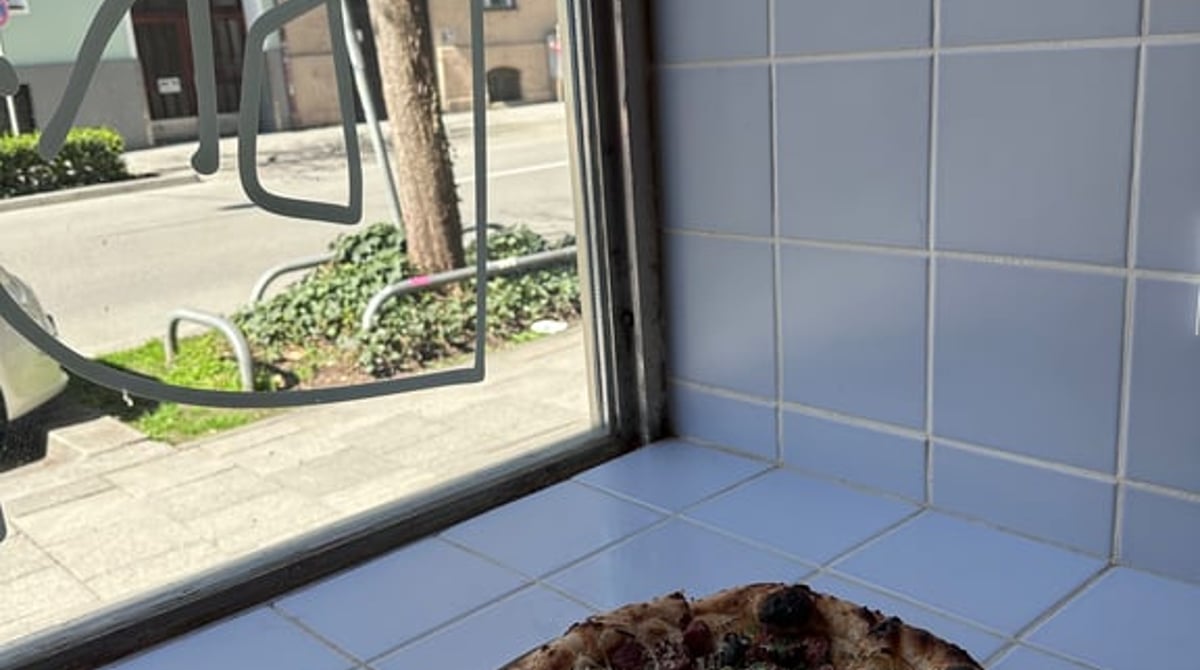 Pizza auf einem Blech vor einem Fenster mit blauen Fliesen im Dr. Drooly in der Häberlstraße