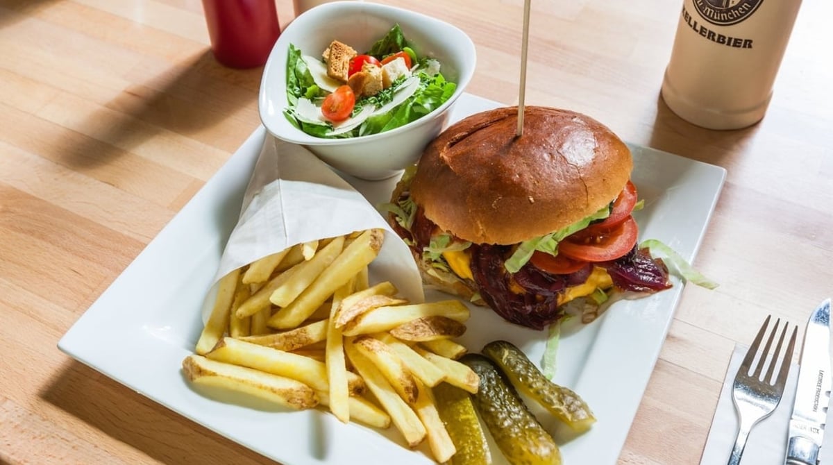 Burger mit Pommes und Gewürzgurken auf einem Teller