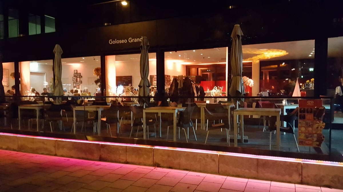 Abendliche Außenansicht des beleuchteten Restaurants Goloseo Grande mit Terrassentischen