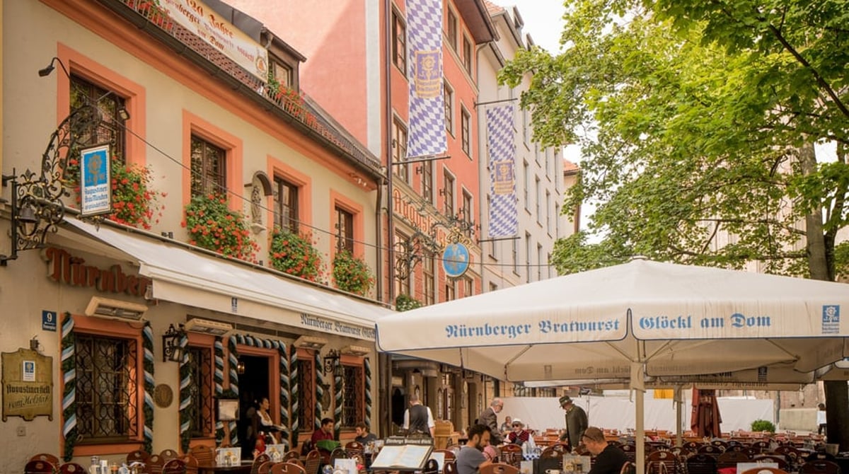 Straßenansicht des Bratwurst Glöckl mit Außenplätzen und Sonnenschirmen am Frauenplatz