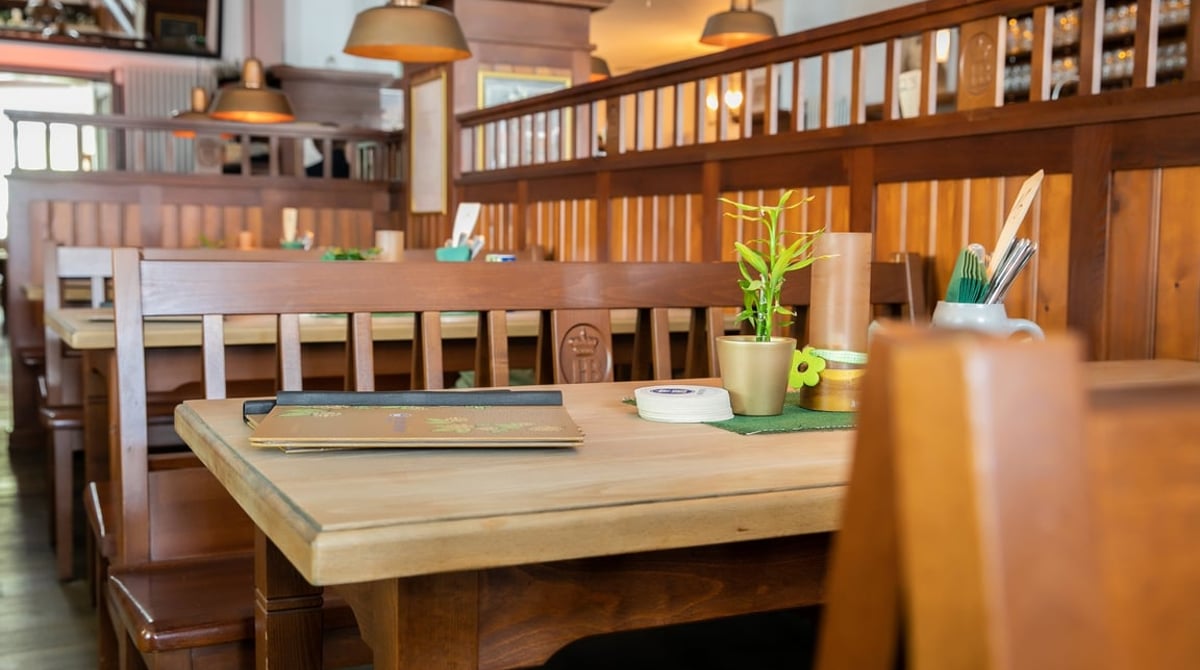 Restaurantbereich im Alten Wirt Moosach mit hellen Holztischen und Holzgeländer