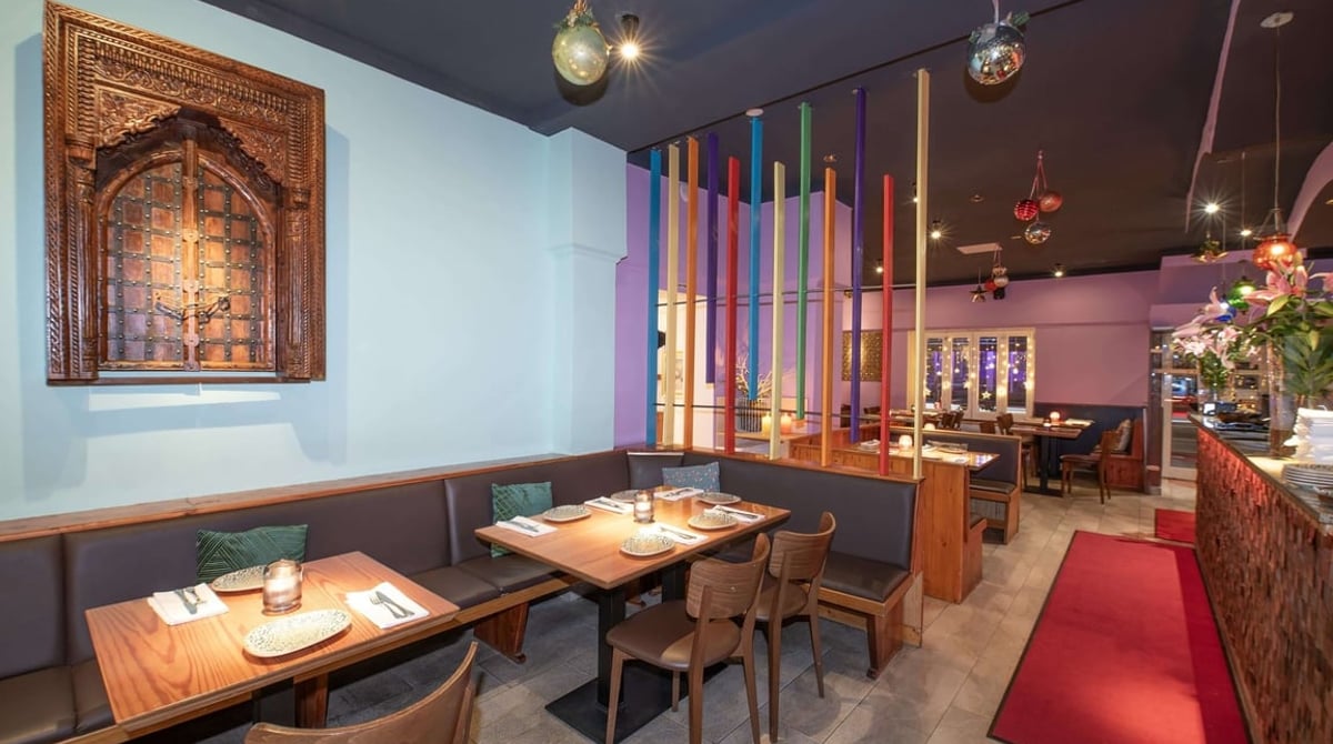 Hellblau gestrichener Gastraum des Dhaba mit geschnitztem Holzfenster an der Wand