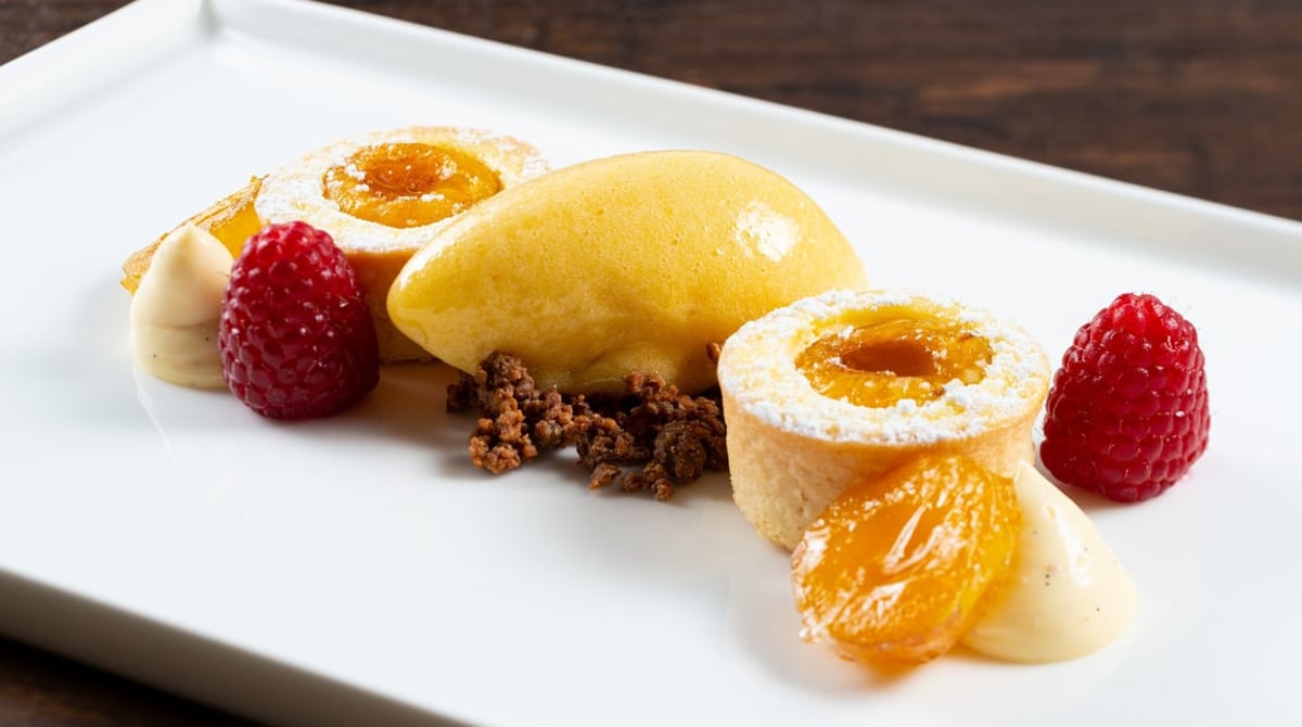Dessert mit Himbeeren, Sorbet und Mürbteigtörtchen auf einem weißen Teller