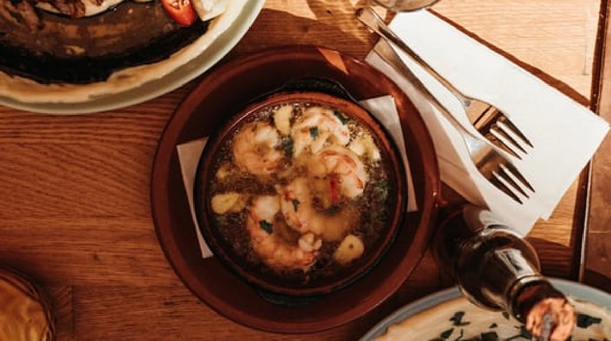 Garnelen in der Tonschale und weitere Tapas auf einem Holztisch