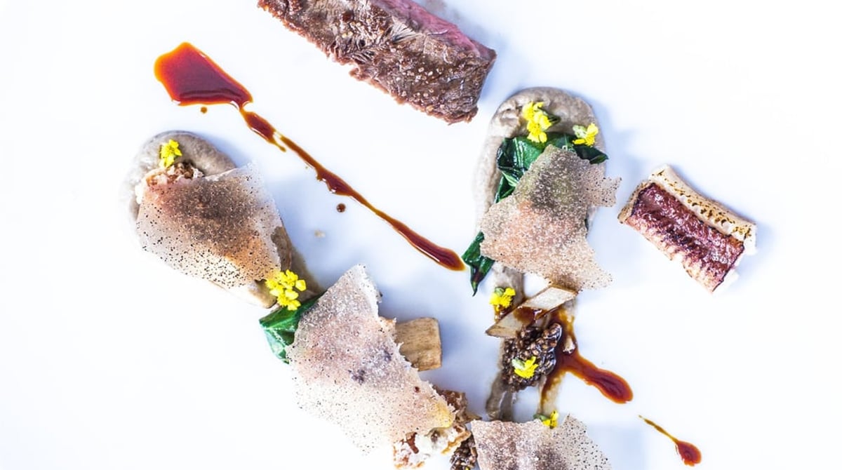Fleischgericht mit Sauce und Blüten, von oben fotografiert