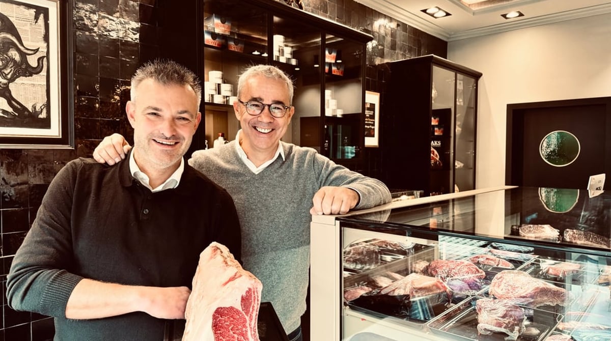 Zwei Männer präsentieren im Verkaufsraum der Fleisch Boutique ein Stück Wagyu vor der Fleischvitrine