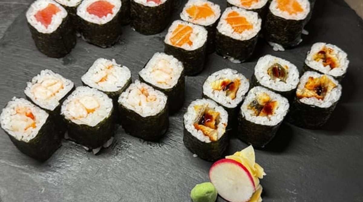 Sushi-Platte mit Nigiri, Maki und essbaren Blüten auf Holz und Schiefer